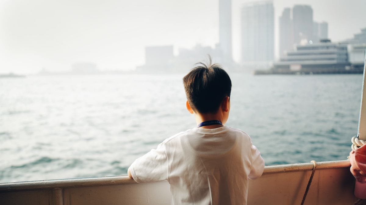 Kind kijkt over de reling van een cruiseschip naar zee
