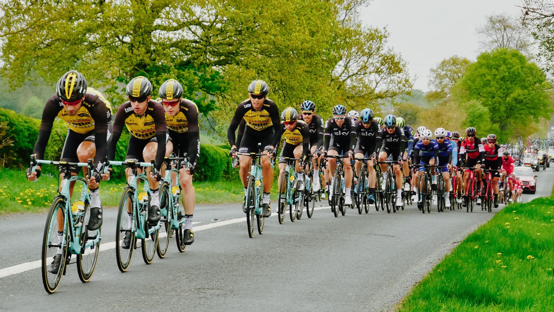 Peloton wielrenners in kleurrijke trui op een landweg tijdens een wielerkoers