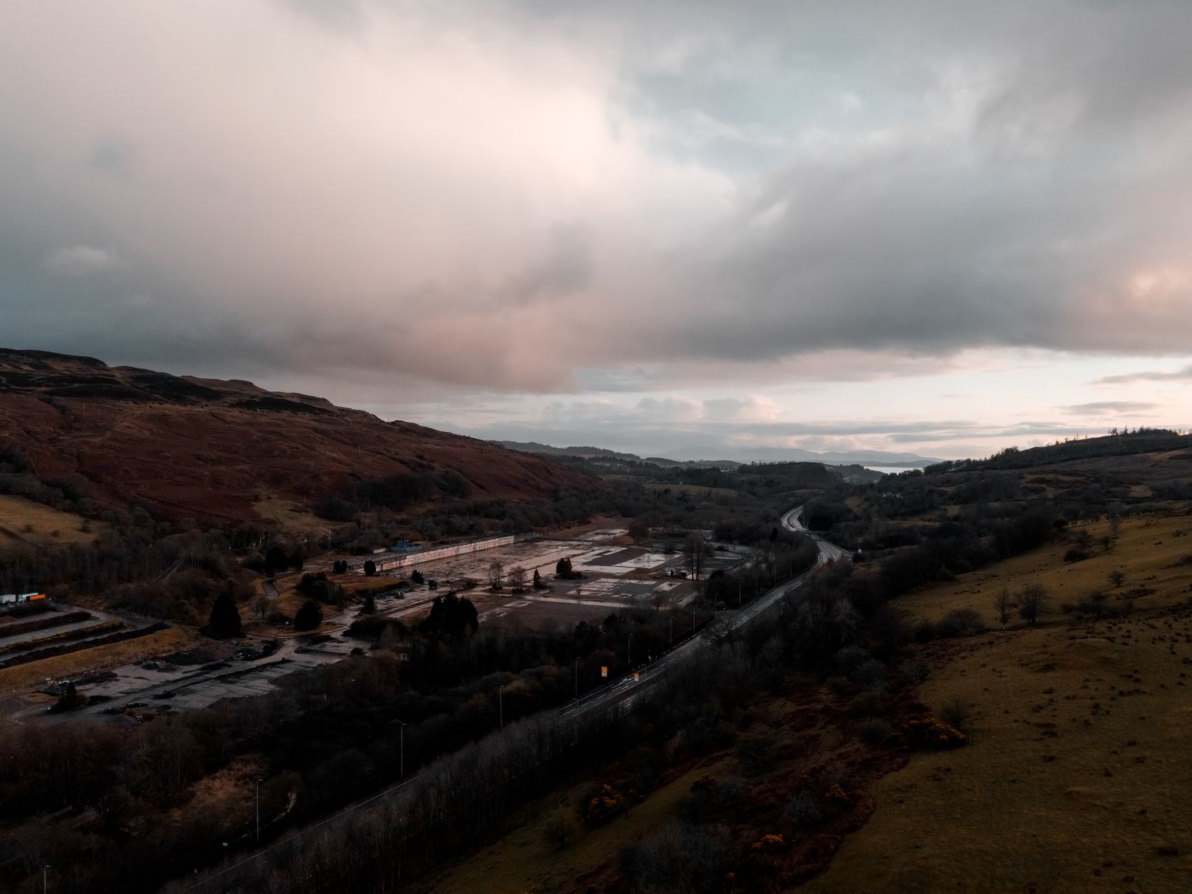 Glooiende heuvels en een lege weg in de Scottish Borders bij bewolkt weer