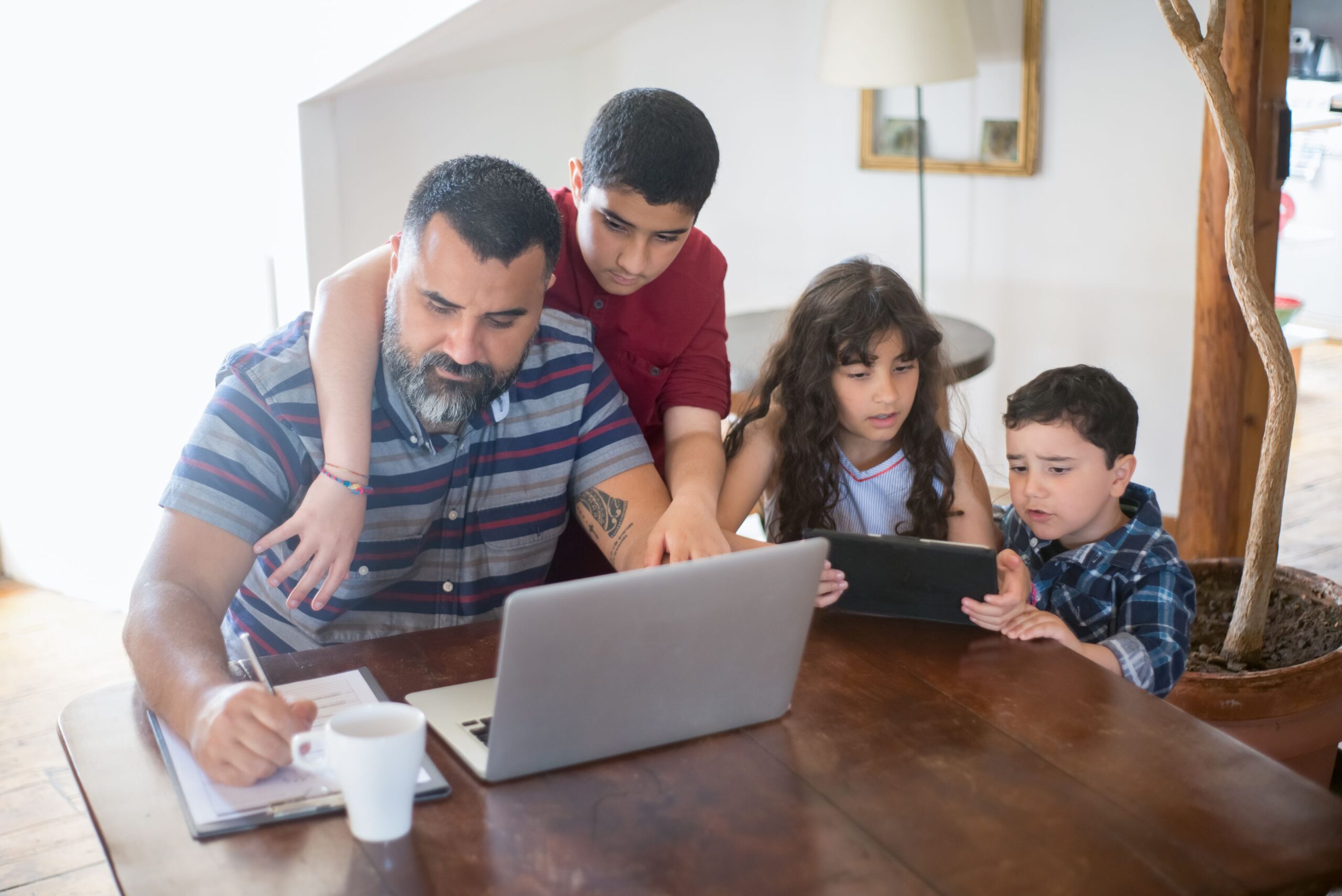 Ouder vraagt op een laptop en tablet de UK ETA aan voor zijn kinderen die zelf nog niet kunnen aanvragen