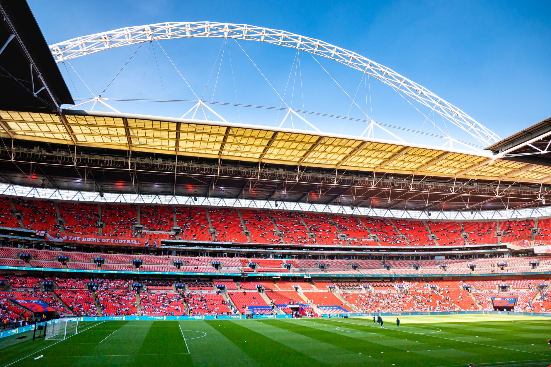 Buitenaanzicht van een groot stadion in Londen met de kenmerkende boog erboven