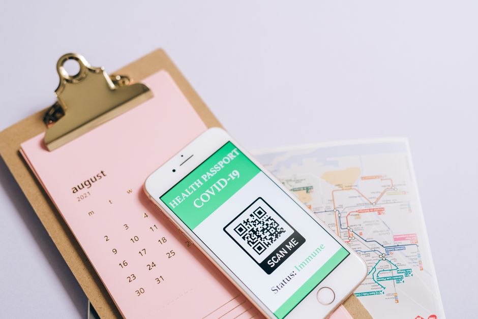 Handen houden een telefoon met een reisdocument-app boven een geopend paspoort op tafel